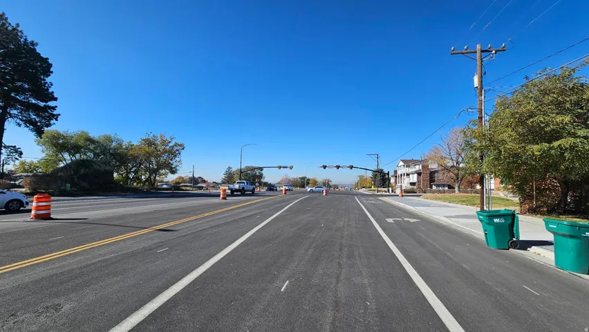 View of asphalt street featuring curbs, sidewalks and street