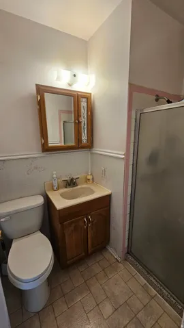 Bathroom featuring vanity, a stall shower, wainscoting, and tile walls