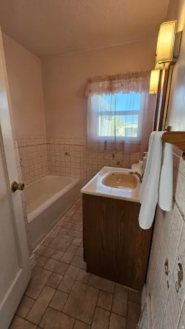 Bathroom with a garden tub, tile walls, a wainscoted wall, a textured ceiling, and vanity
