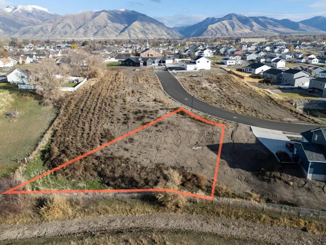 Aerial view of residential area with property boundaries highlighted and a mountain backdrop