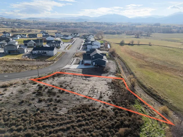 Aerial view of residential area with property boundaries highlighted and a mountainous background