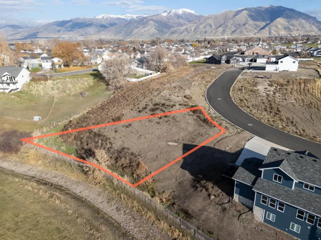 Aerial perspective of suburban area featuring a mountain backdrop and property parcel outlined