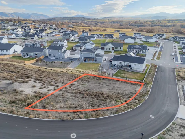 Aerial perspective of suburban area with property parcel outlined and a mountainous background