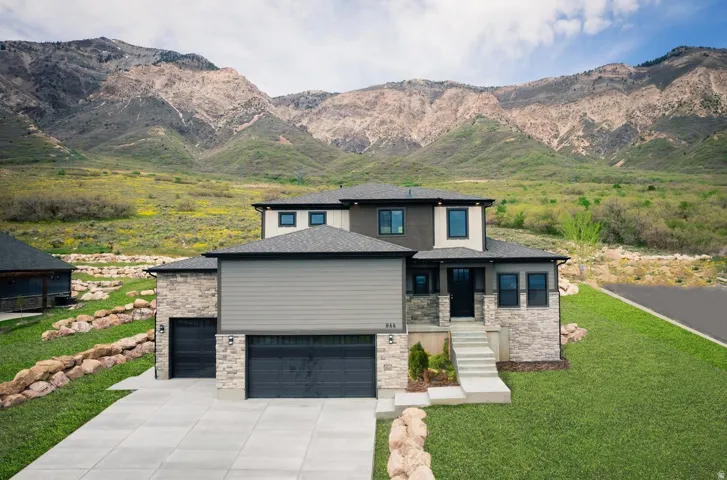 View of front of property featuring a mountain view, driveway, a front yard, a shingled roof, and a garage