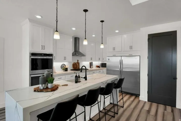 Kitchen featuring appliances with stainless steel finishes, decorative light fixtures, dark wood finished floors, light stone counters, and recessed lighting
