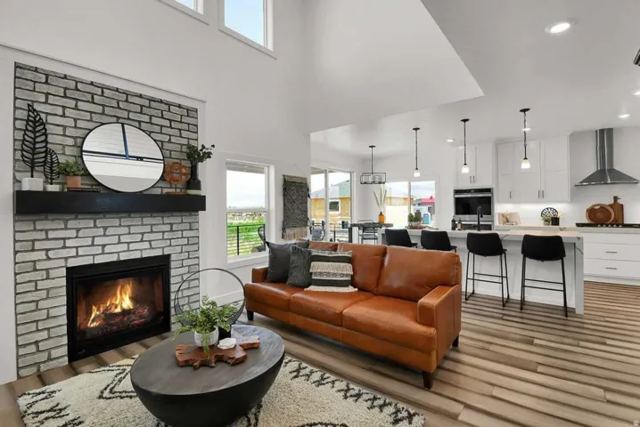 Living room featuring healthy amount of natural light, light wood-style floors, a fireplace, recessed lighting, and a towering ceiling