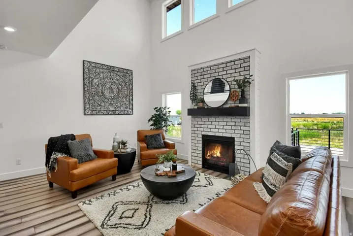 Living area with a towering ceiling, a brick fireplace, and wood finished floors