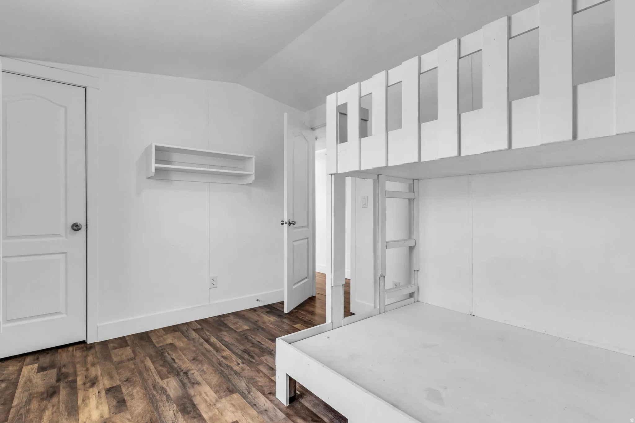 Unfurnished bedroom featuring dark wood-style flooring and lofted ceiling