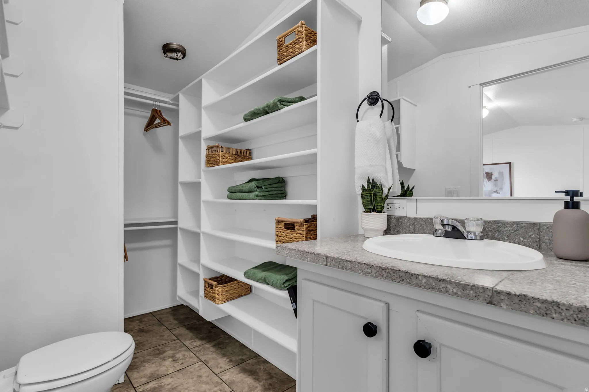 Bathroom with vanity, vaulted ceiling, dark tile patterned flooring, and a closet