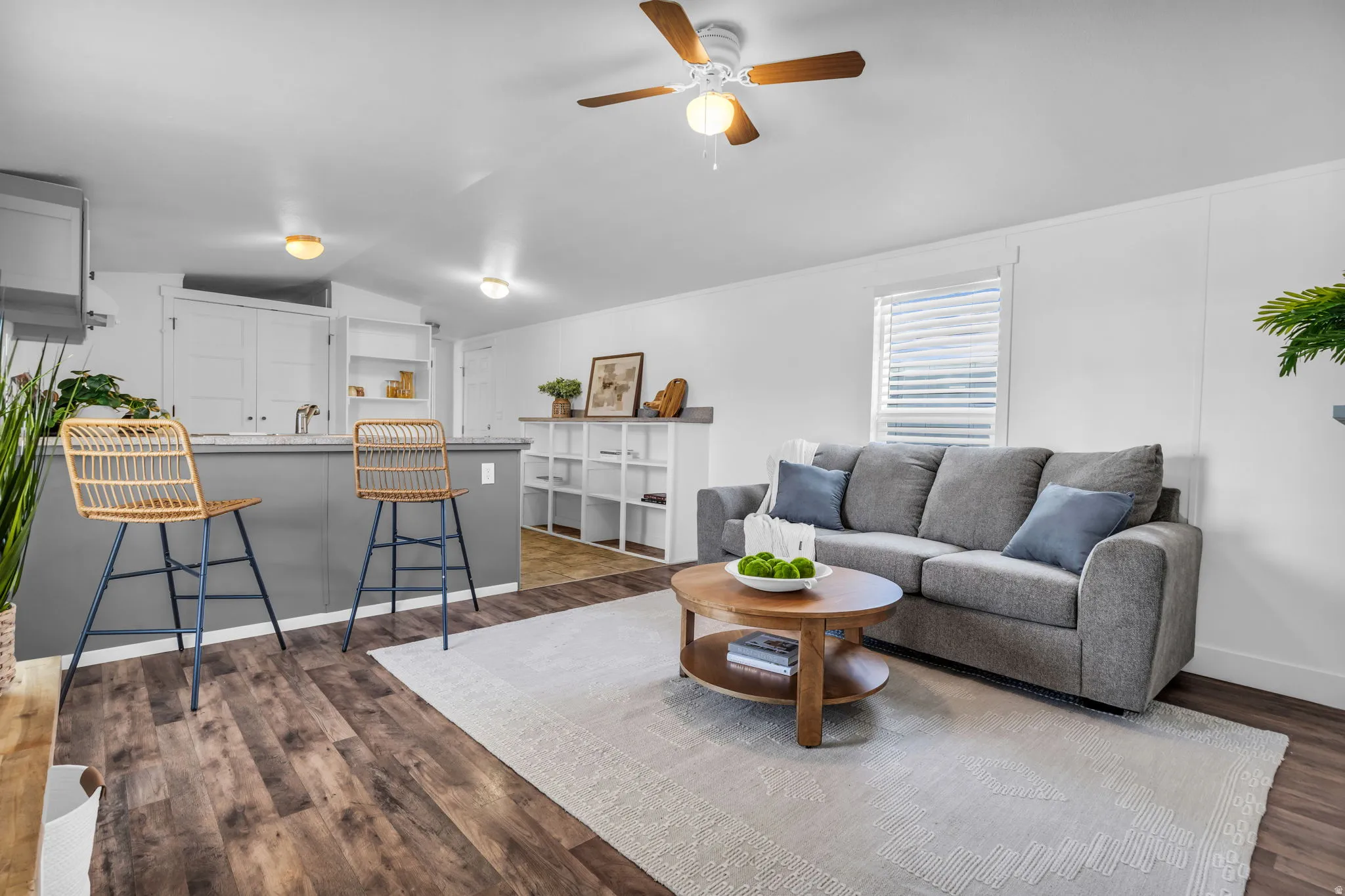 Living area with vaulted ceiling, dark wood-style flooring, and ceiling fan