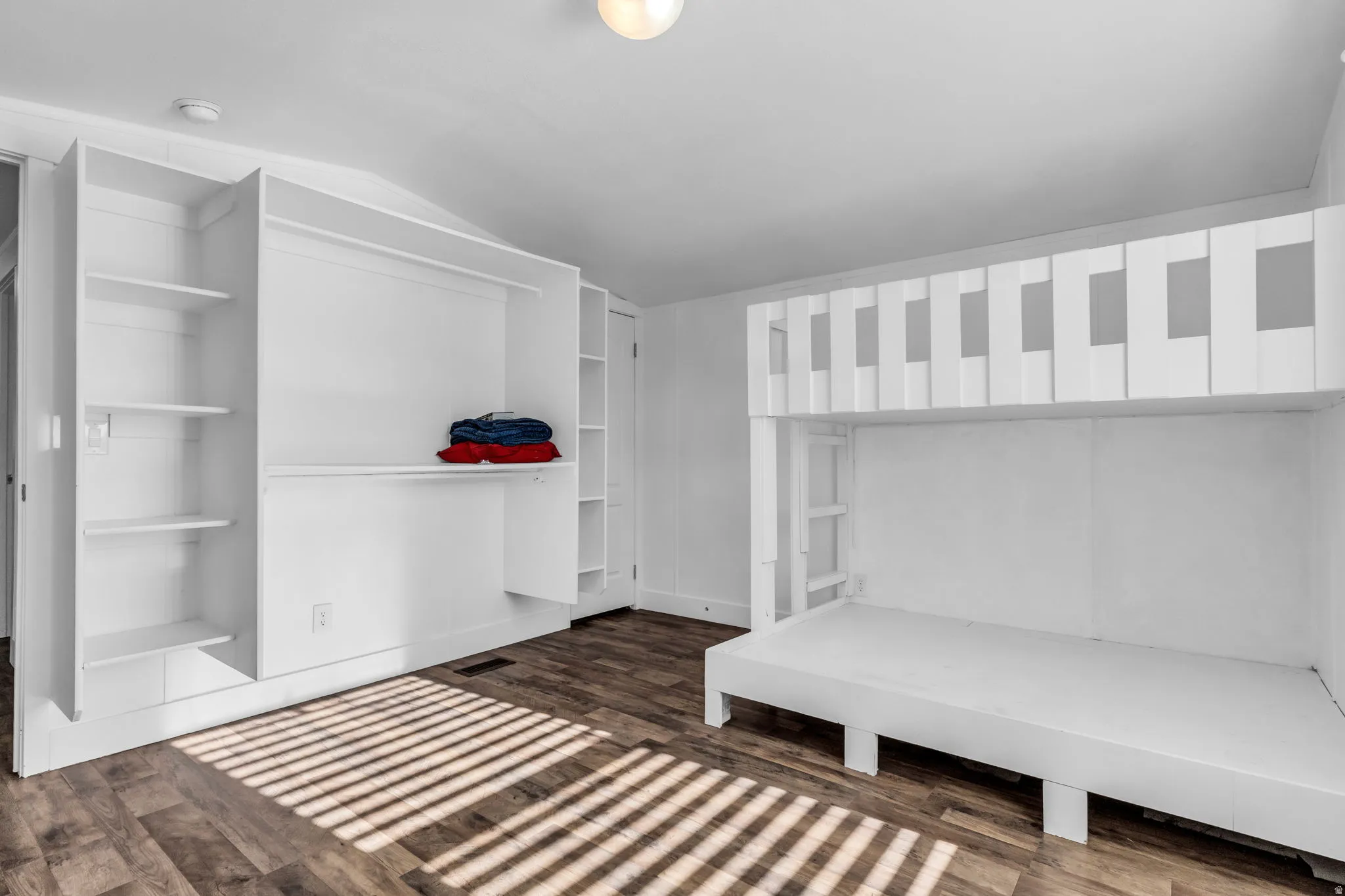 Unfurnished bedroom featuring lofted ceiling and dark wood-style flooring