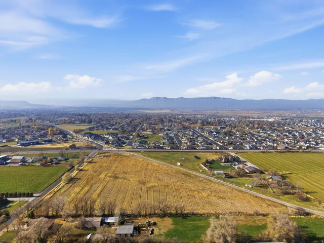 Aerial view of property's location featuring a mountainous background, nearby suburban area, and abundant farmland