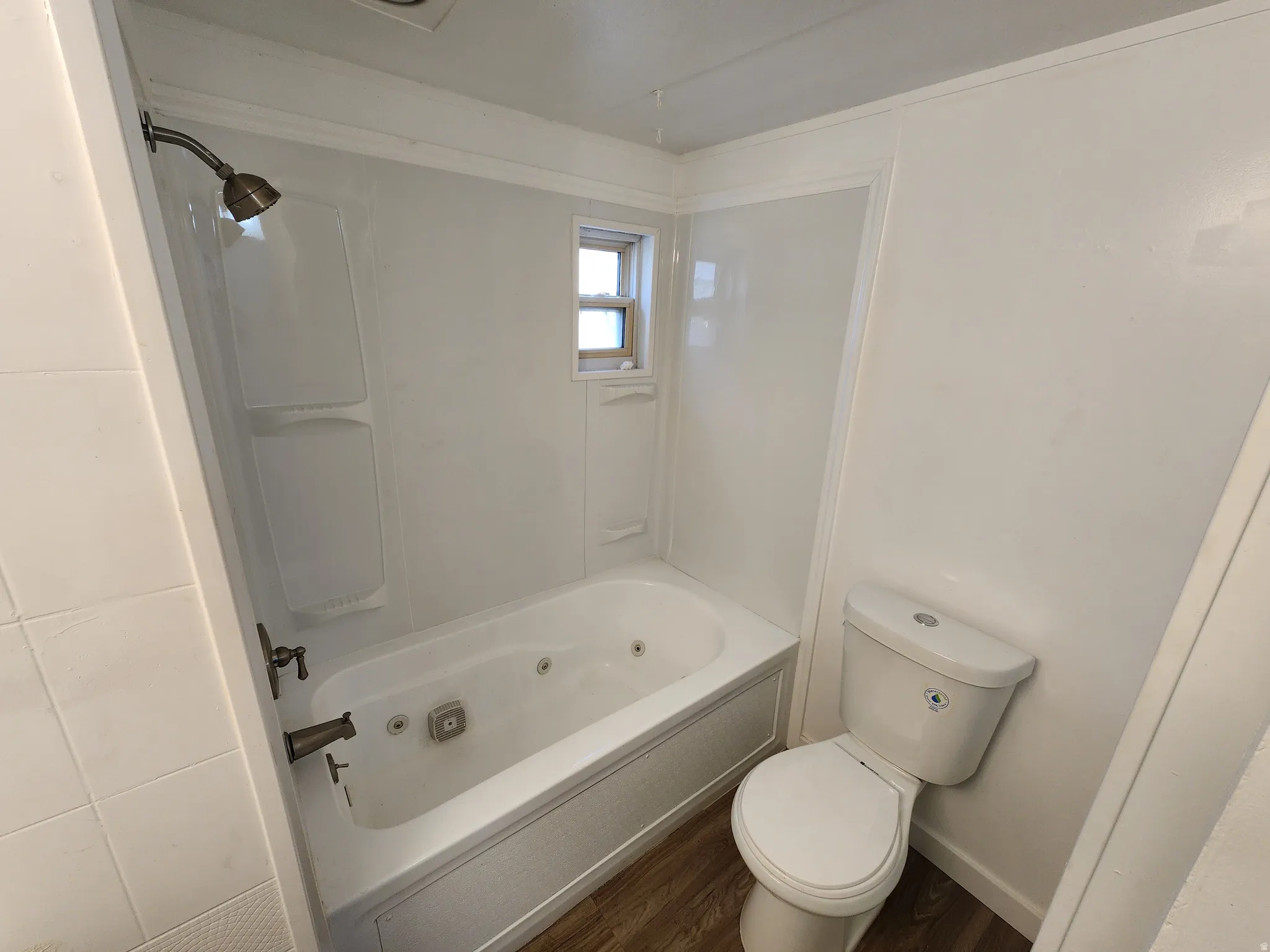 Bathroom featuring dark wood-type flooring and a combined bath / shower with jetted tub