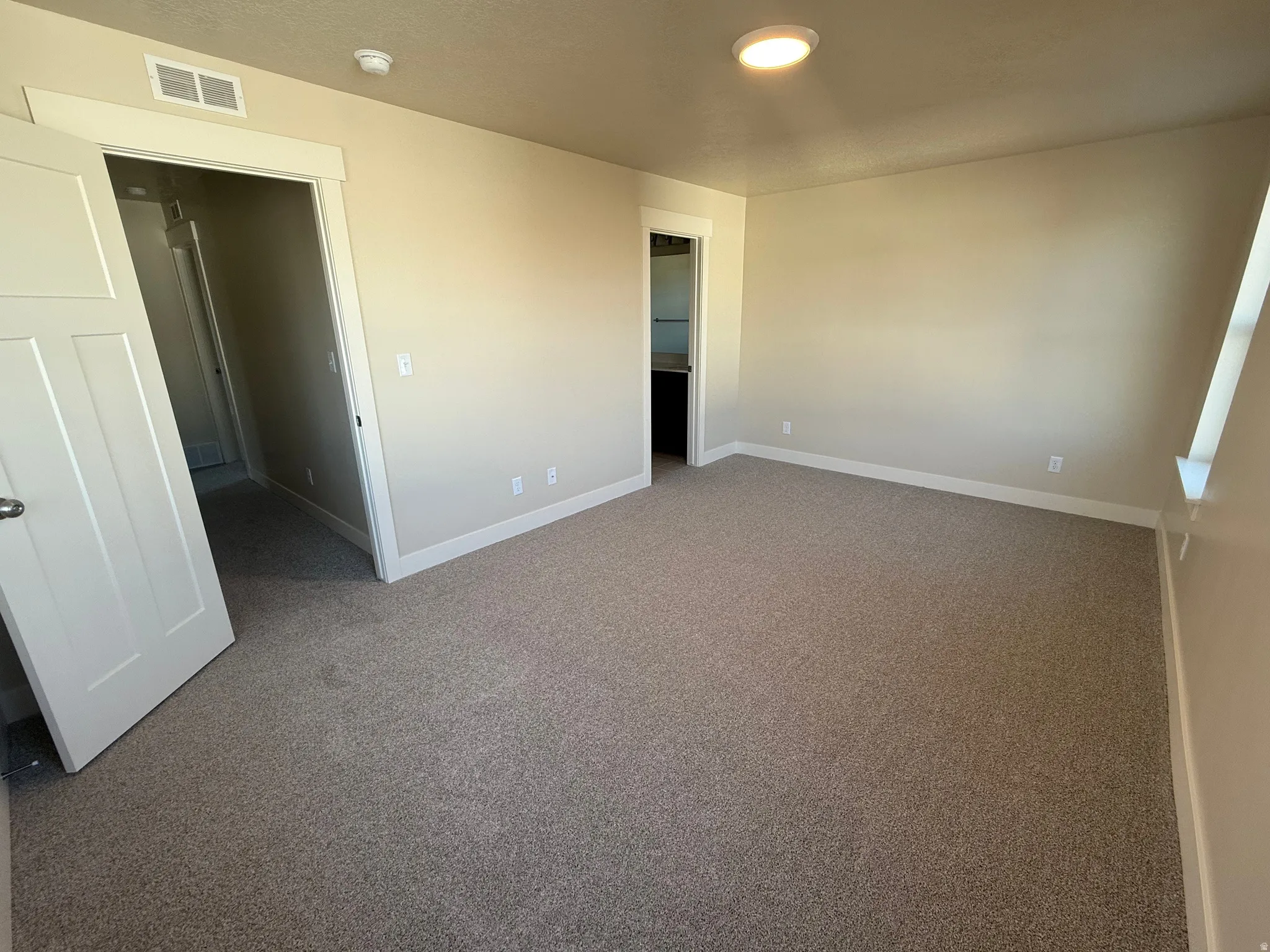 Unfurnished bedroom featuring light carpet and baseboards