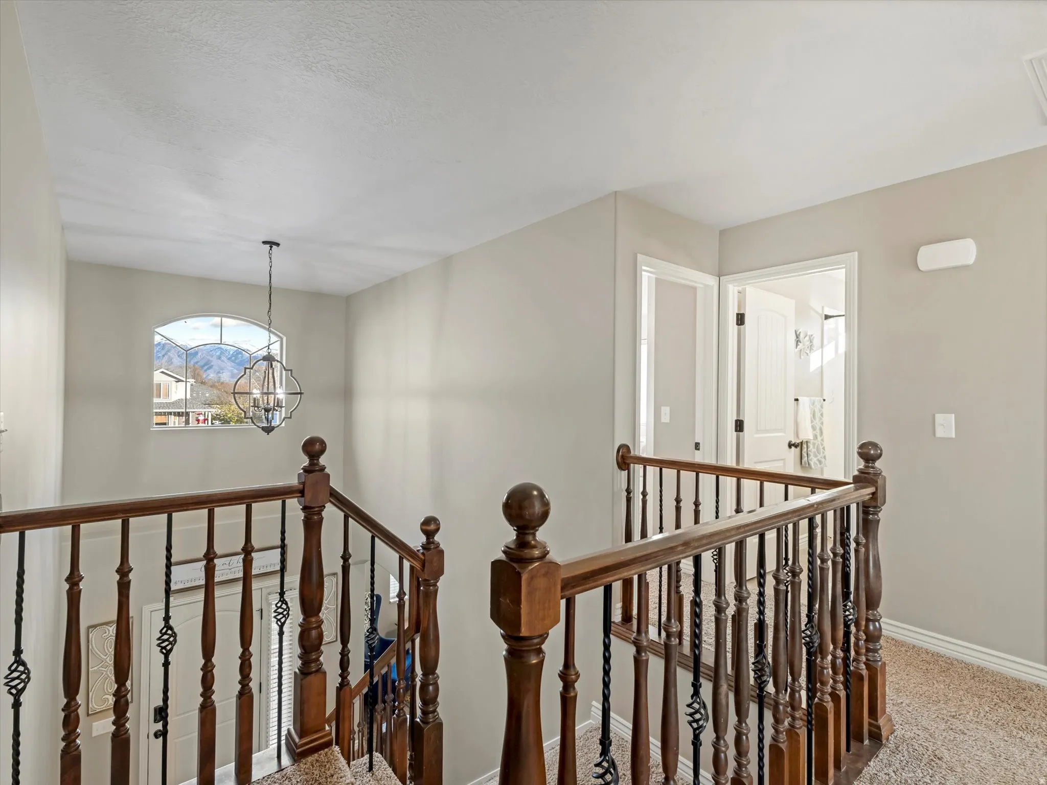 Corridor featuring an upstairs landing, a chandelier, and carpet