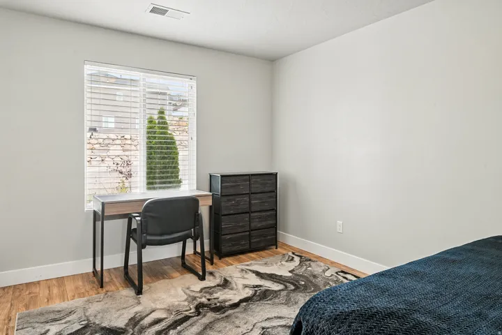Bedroom with wood finished floors and a desk