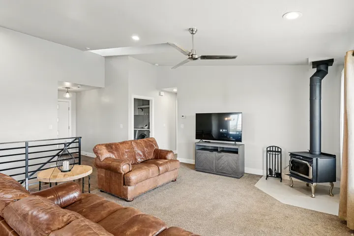 Carpeted living room with a wood stove, a ceiling fan, recessed lighting, and a towering ceiling