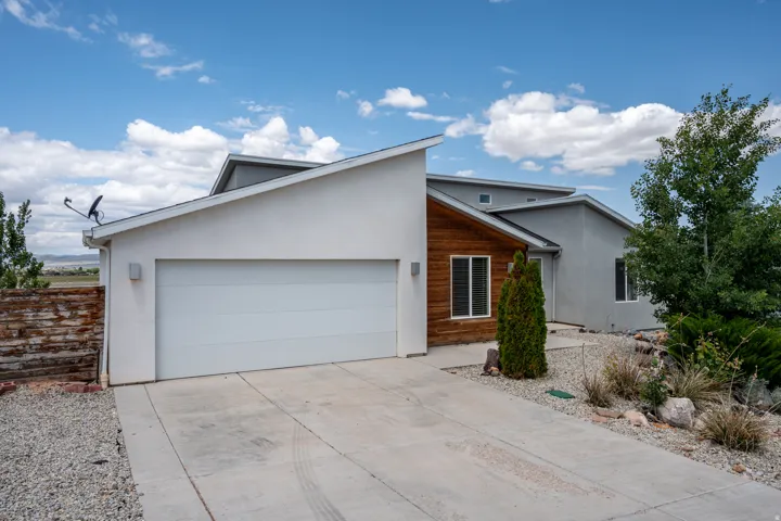 View of front of house with stucco siding, driveway, and a garage