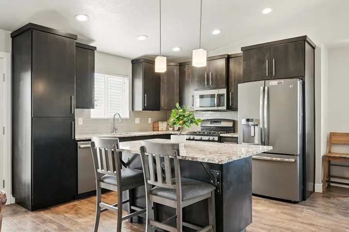 Kitchen featuring appliances with stainless steel finishes, light stone counters, a breakfast bar, a kitchen island, and hanging light fixtures
