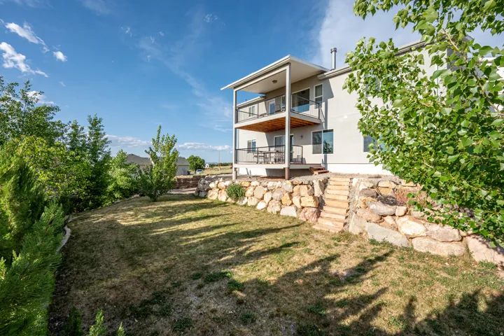 Rear view of property featuring a lawn and a balcony