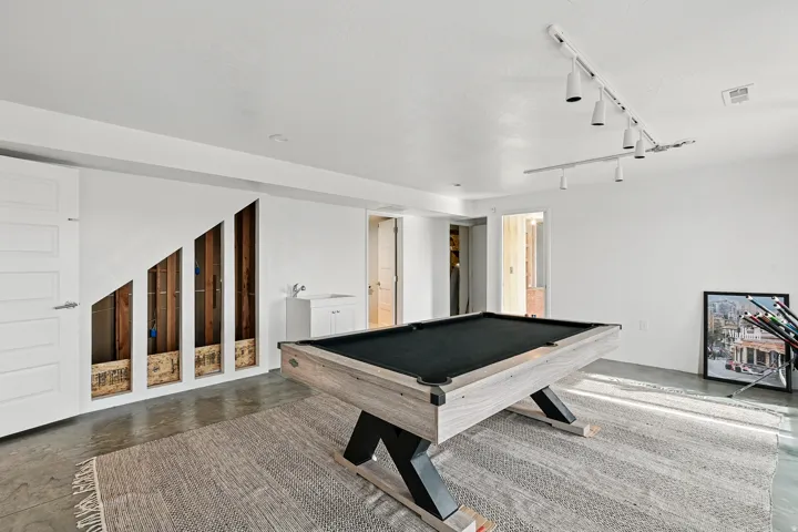 Recreation room featuring finished concrete flooring, billiards table, and track lighting