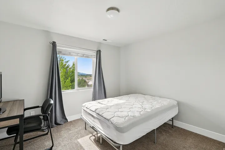 Bedroom with light carpet and an office area