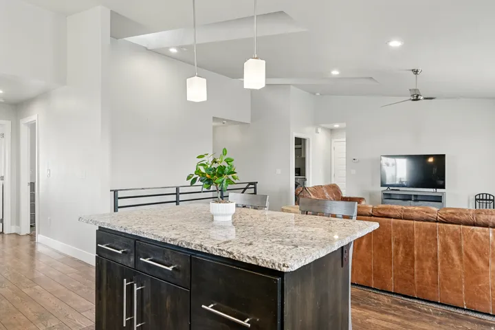 Kitchen with light stone counters, pendant lighting, dark wood-style floors, a center island, and open floor plan