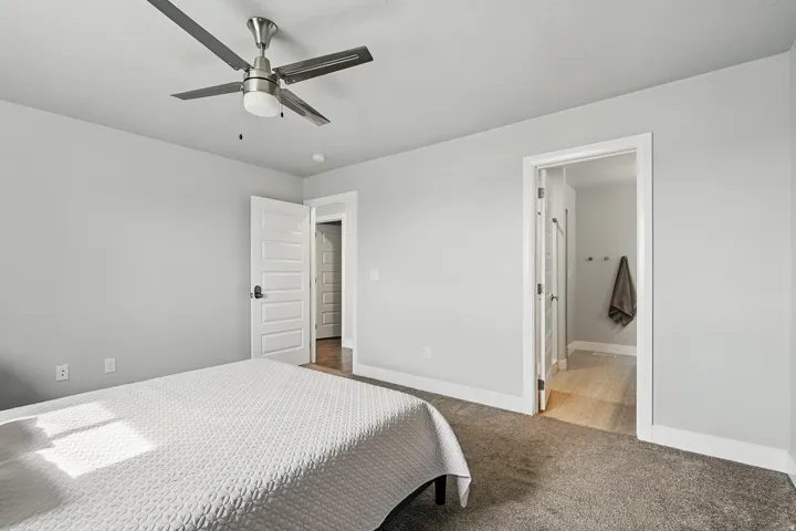 Carpeted bedroom with a ceiling fan and ensuite bath