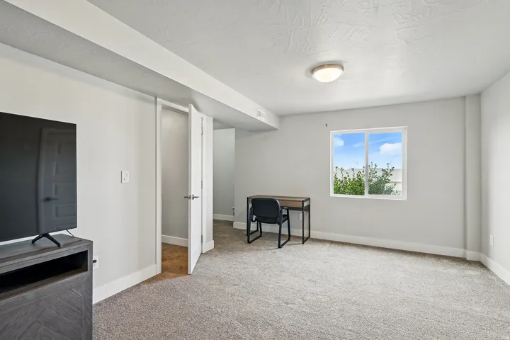 Bedroom featuring light carpet, an office area, and a textured ceiling