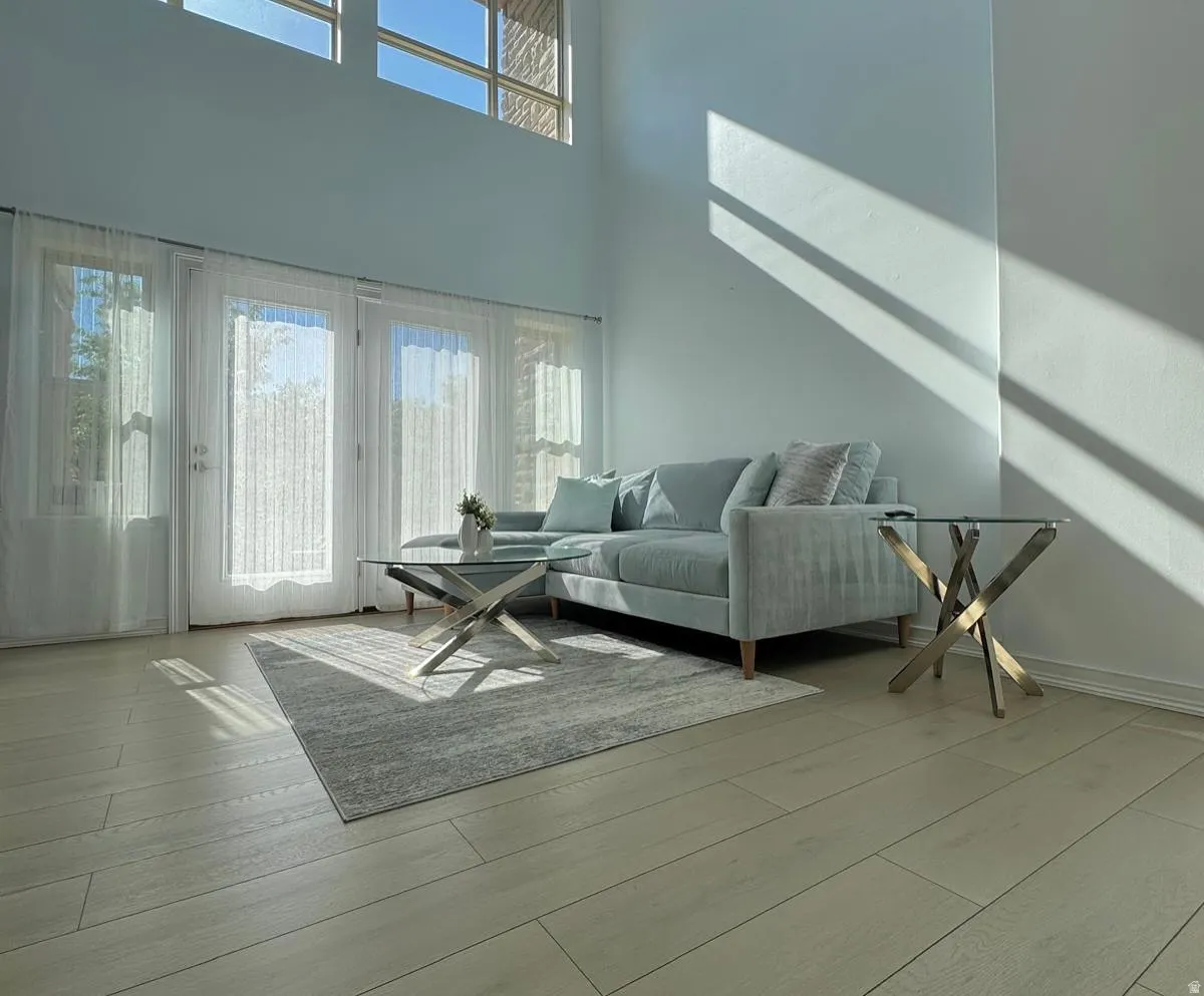 Living area featuring plenty of natural light, light wood-style floors, and a towering ceiling