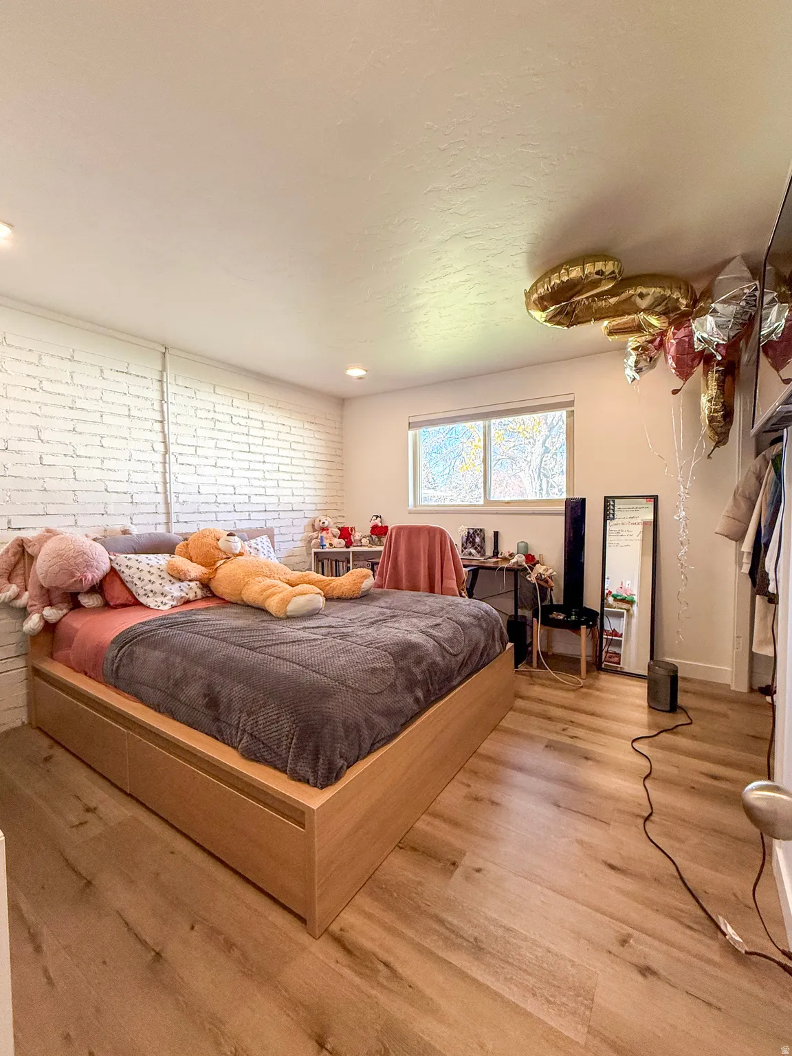 Bedroom featuring brick wall and light wood-style flooring