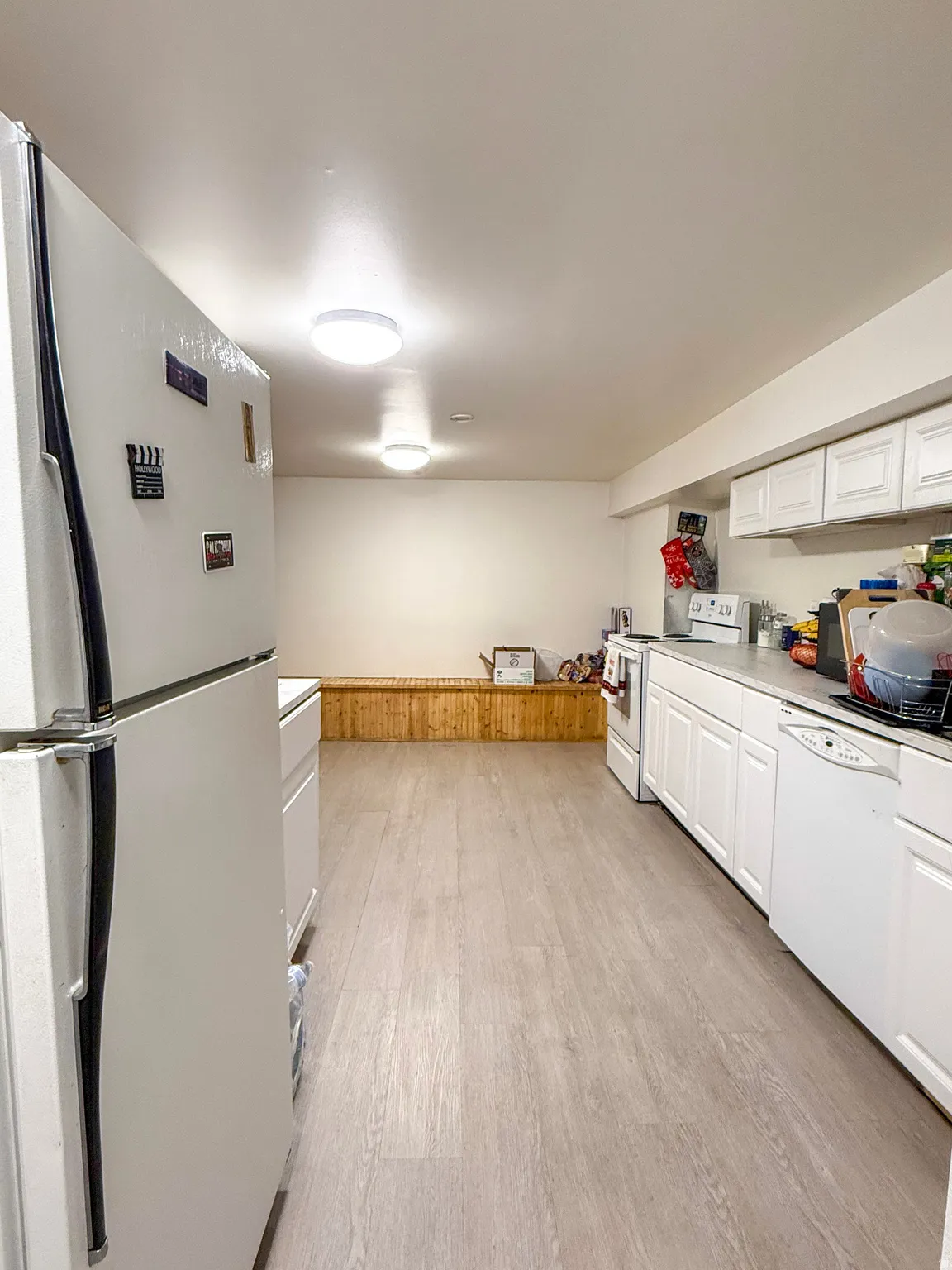 Kitchen with white appliances, white cabinetry, light countertops, light wood-style flooring, and wainscoting