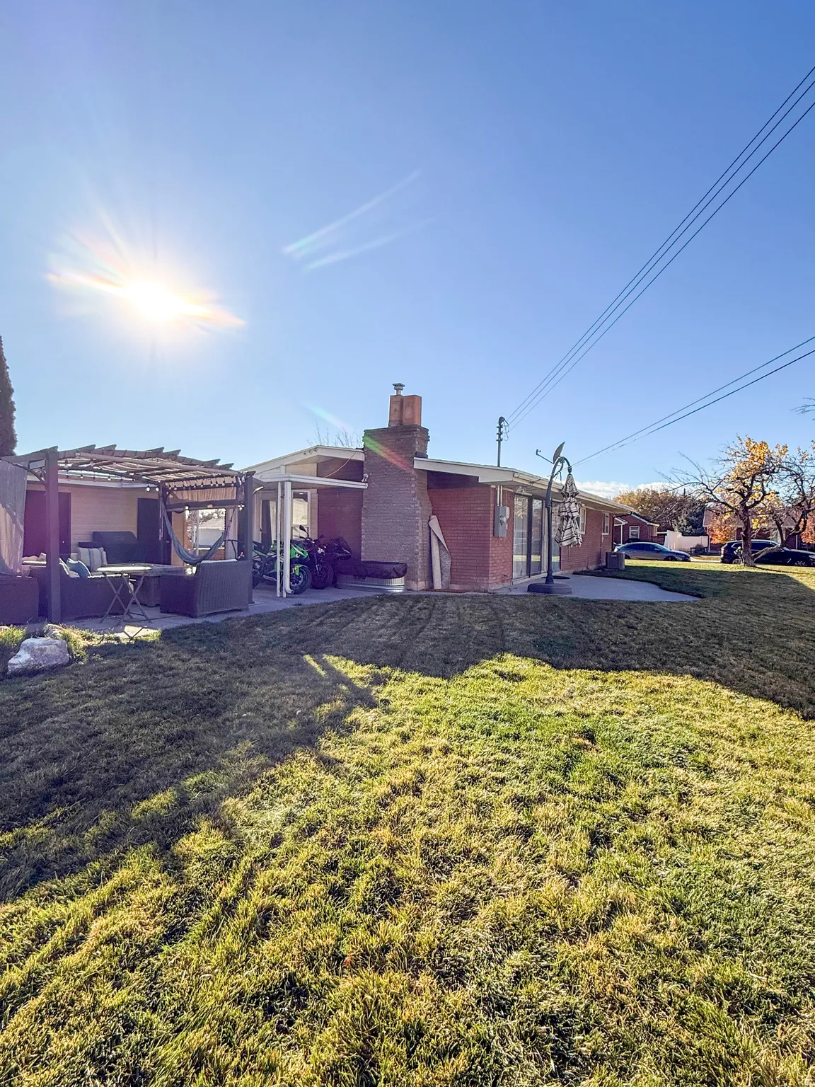 Back of property featuring a yard, a chimney, a patio area, brick siding, and a pergola