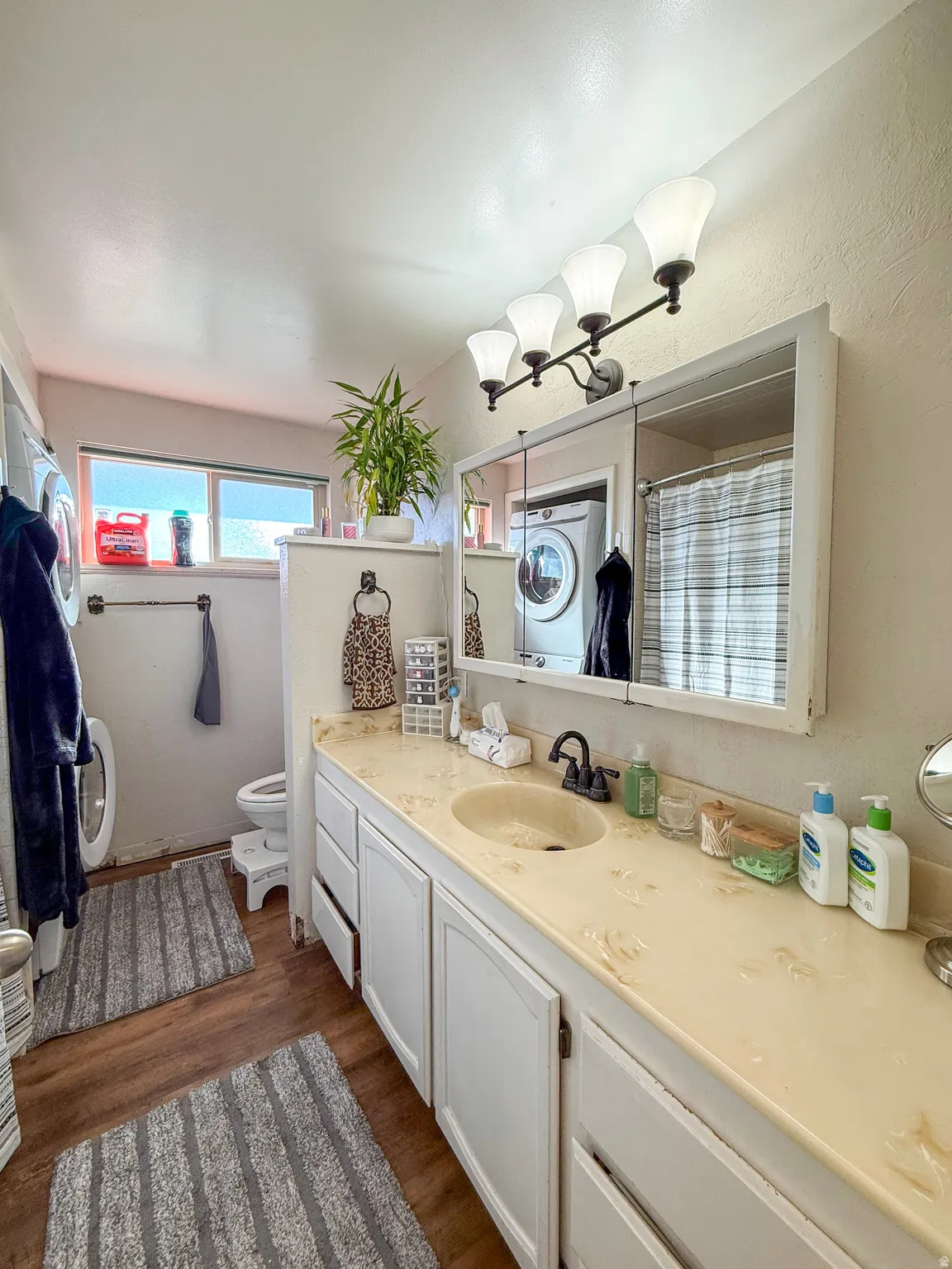 Bathroom featuring vanity, a shower with curtain, dark wood-style flooring, and washer / dryer