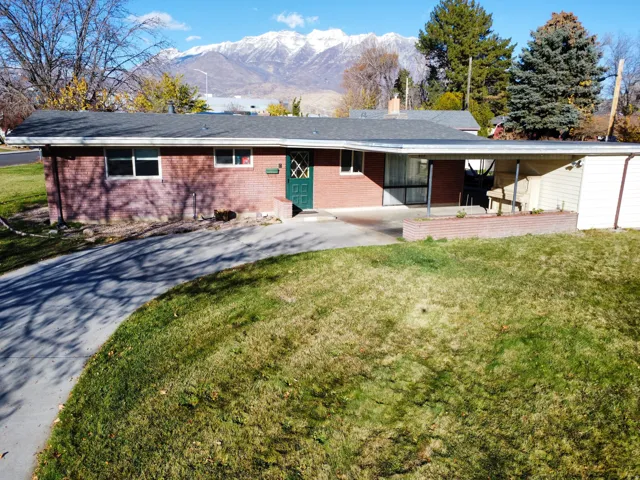 Single story home with brick siding, a front lawn, and a mountain view