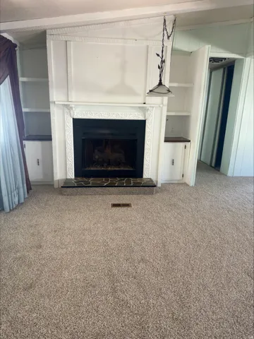 Living space featuring a central fireplace with an ornate white mantel and black firebox