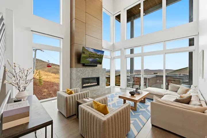 Living room with a high end fireplace, hardwood / wood-style flooring, and a high ceiling