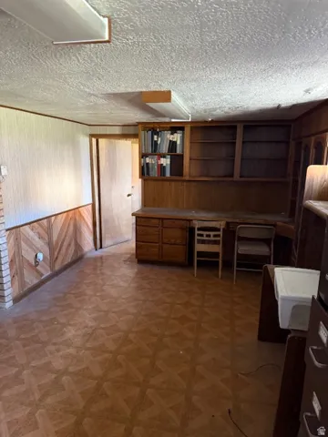 Unfurnished office featuring wood walls, a textured ceiling, and tile patterned floors
