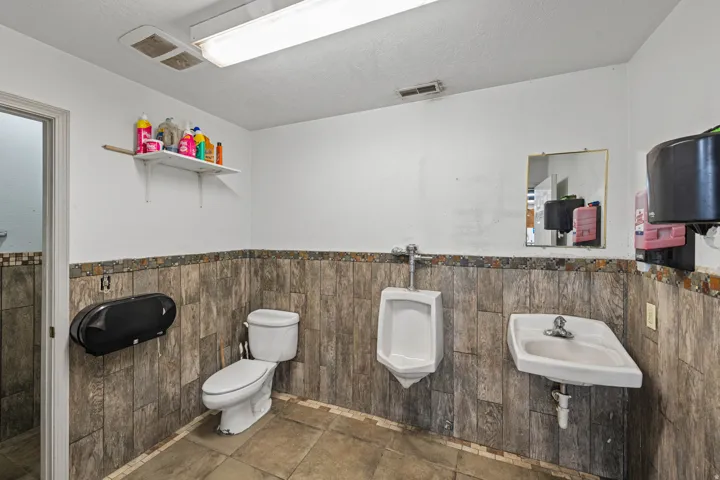 Half bathroom with a wainscoted wall, a textured ceiling, and tile walls