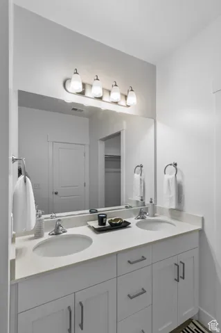 Full bath featuring double vanity and a walk in closet
