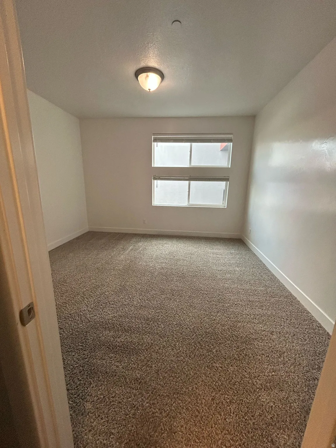 Carpeted empty room featuring a textured ceiling and baseboards