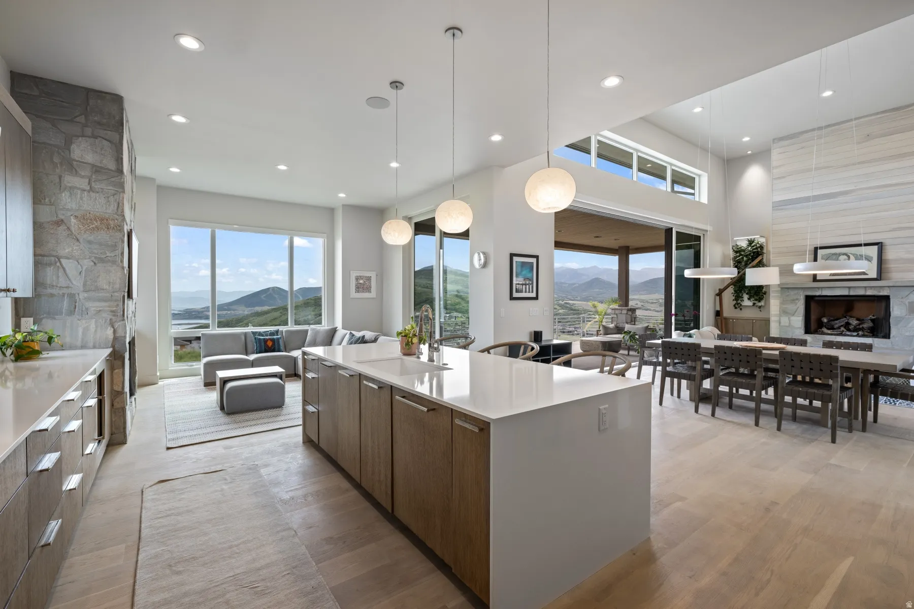 Kitchen featuring open floor plan, modern cabinets, light stone countertops, hanging light fixtures, and light wood-style floors