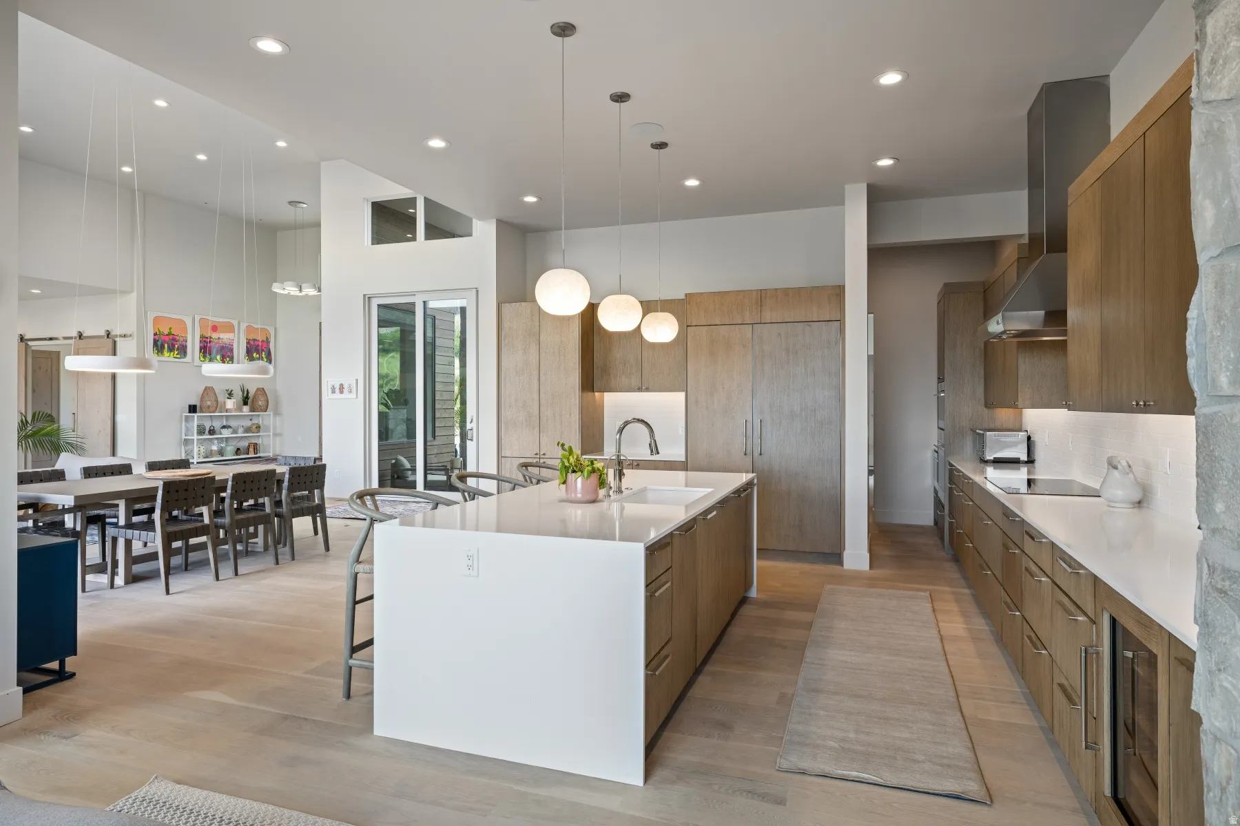 Kitchen with a breakfast bar area, light stone counters, decorative light fixtures, light wood-type flooring, and modern cabinets