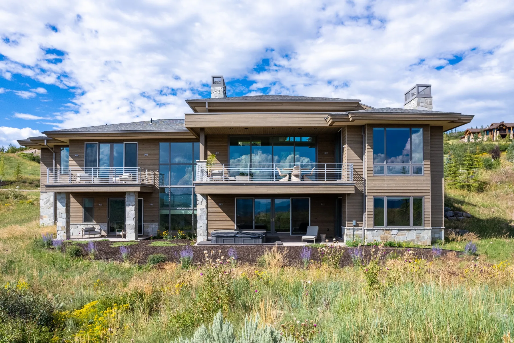 Rear view of property with a chimney, a balcony, a patio area, and a hot tub