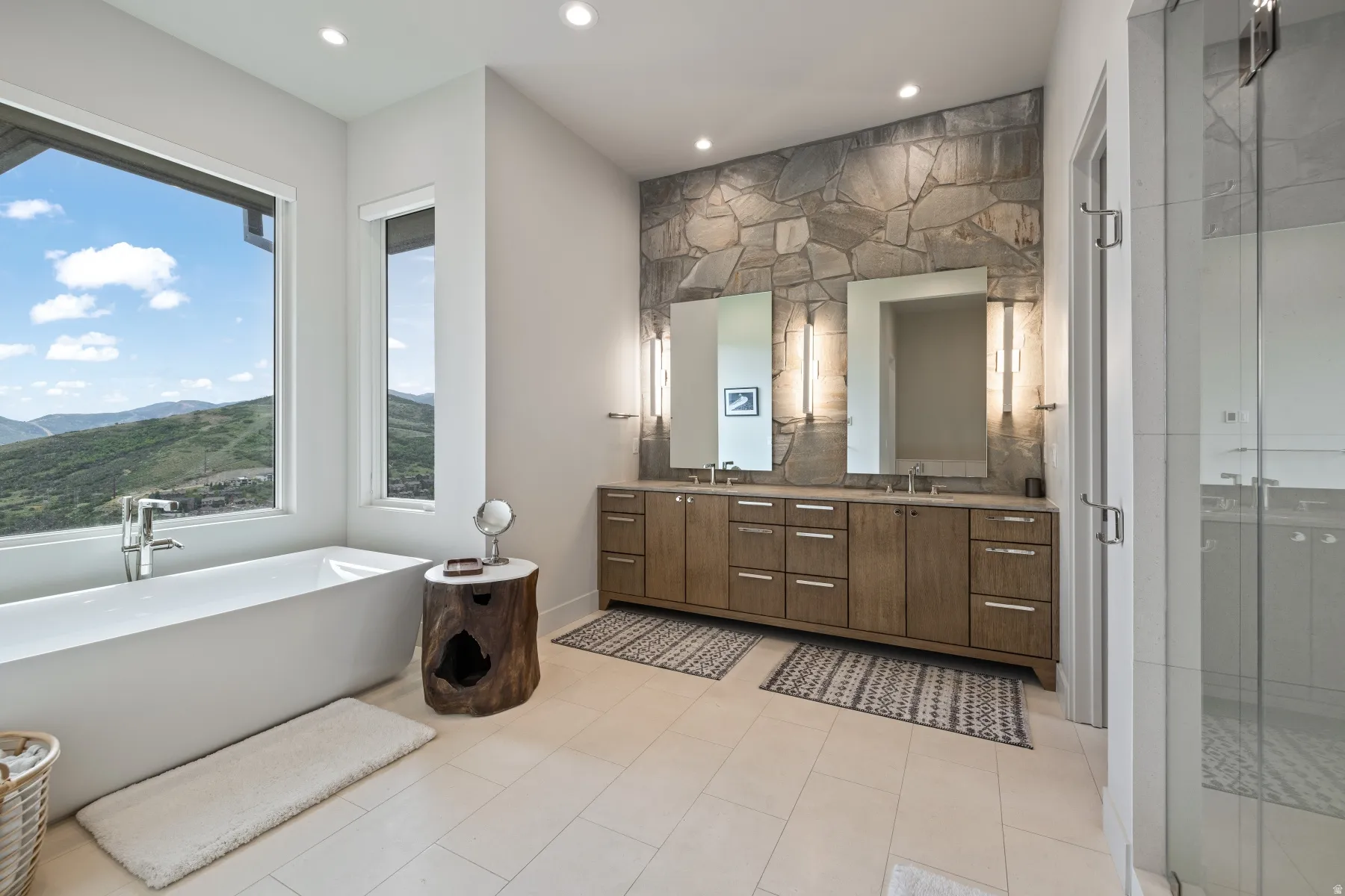 Full bathroom with double vanity, a shower stall, a freestanding tub, a mountain view, and recessed lighting