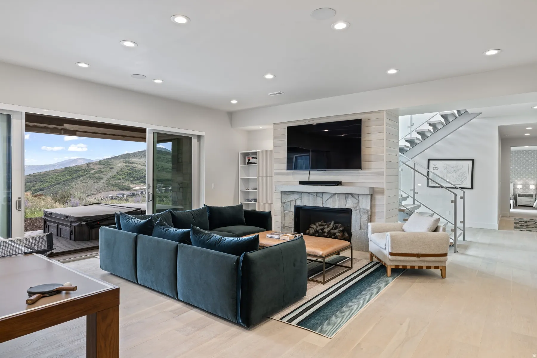 Living room featuring a premium fireplace, light wood finished floors, recessed lighting, a mountain view, and stairs
