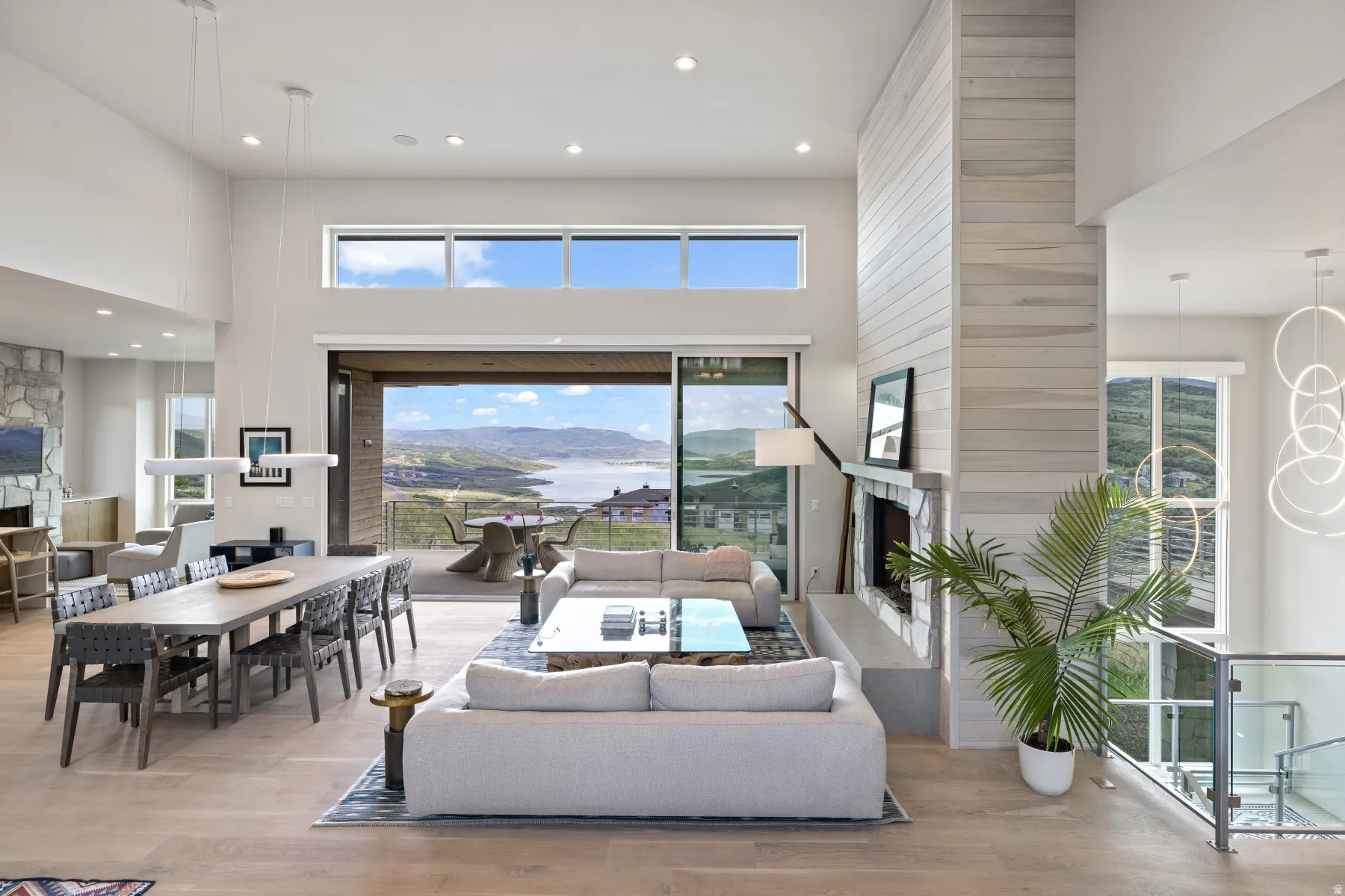 Living room with a large fireplace, a towering ceiling, plenty of natural light, recessed lighting, and light wood-style flooring