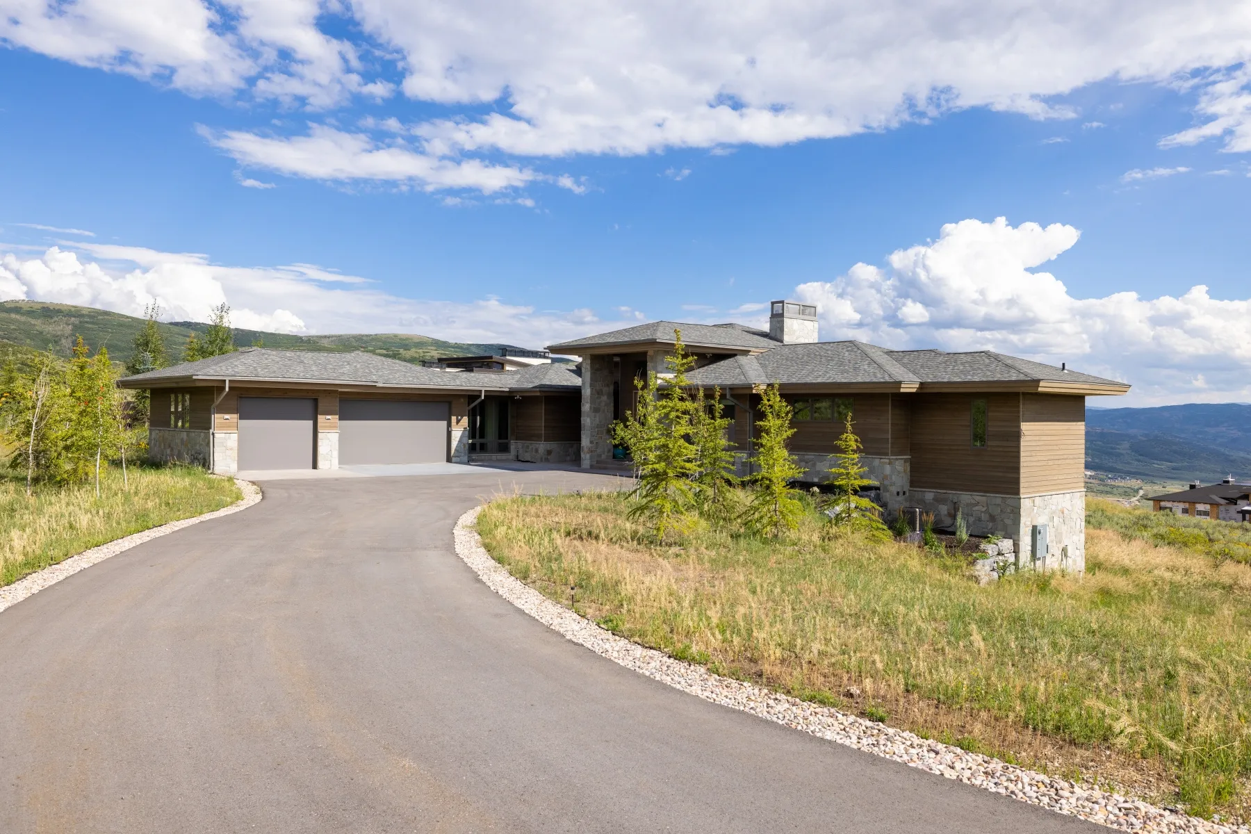 Prairie-style home featuring stone siding, a chimney, a mountain view, an attached garage, and asphalt driveway