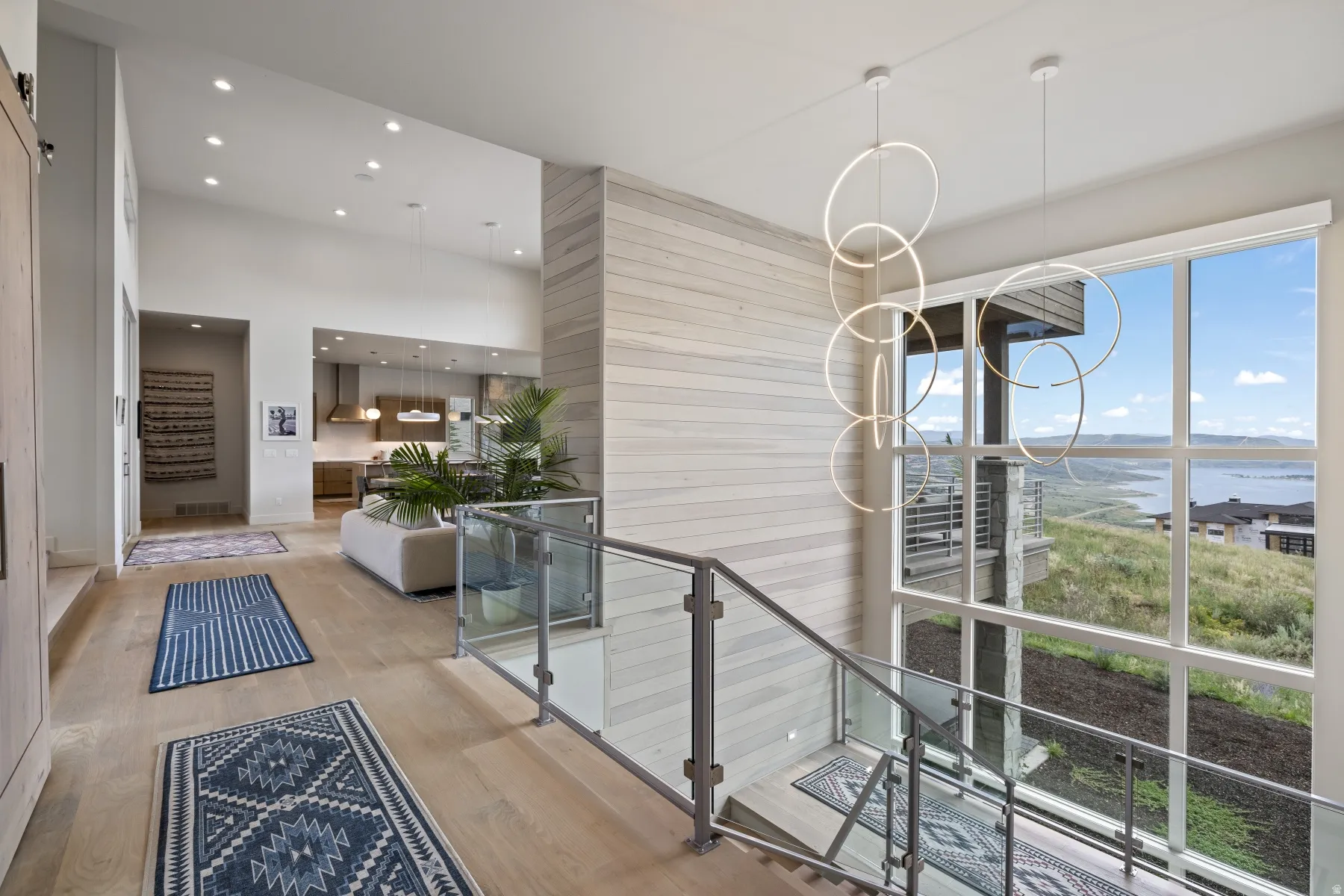 Corridor featuring a water view, wood finished floors, a towering ceiling, recessed lighting, and wood walls