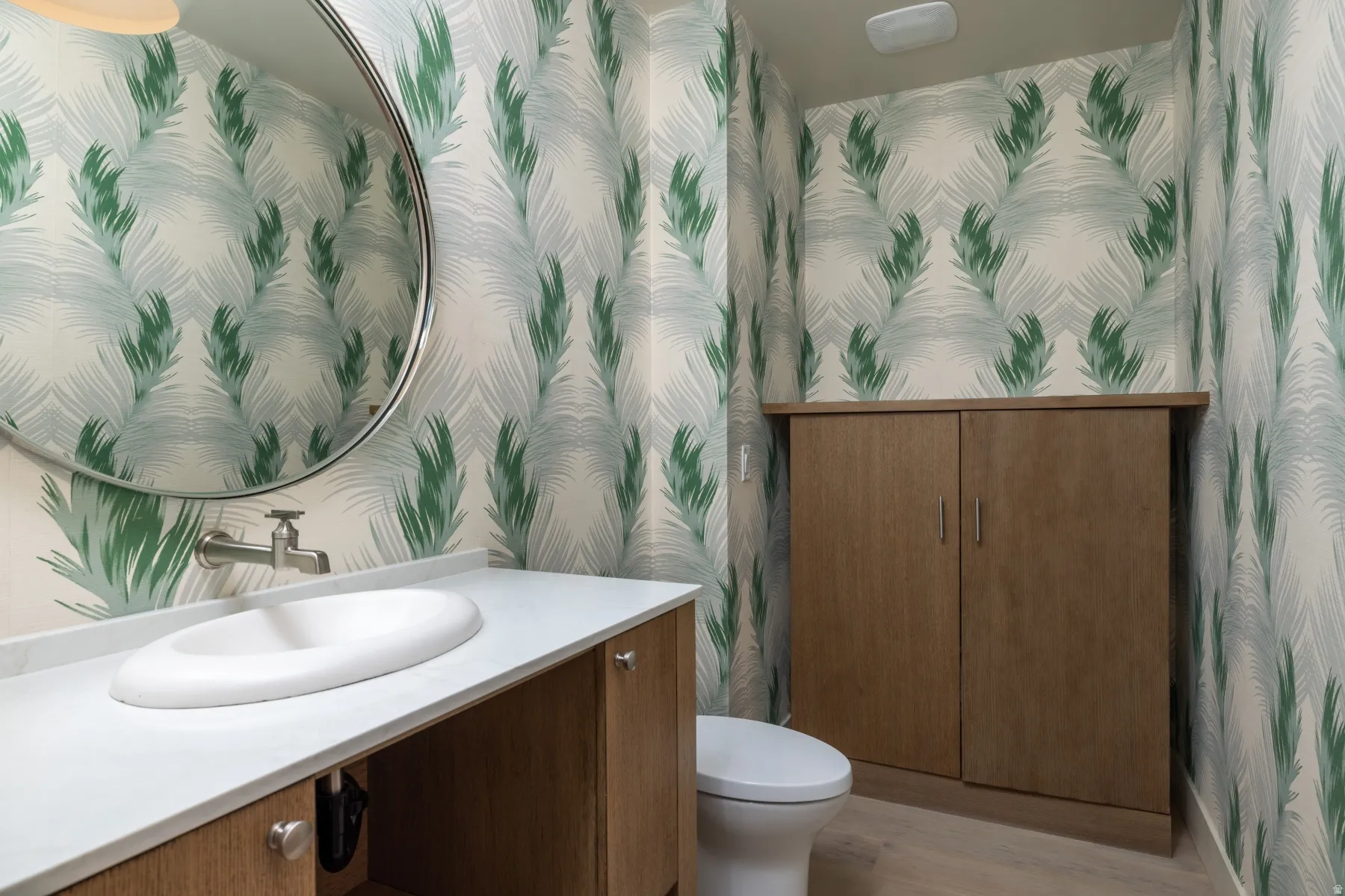 Bathroom with wallpapered walls, vanity, and light wood-style flooring